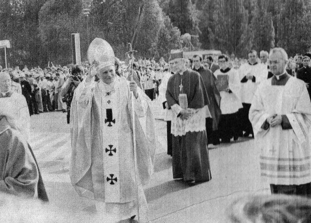 Jan Paweł II w ornacie i mitrze, z pastorałem, błogosławi idąc w procesji w Warszawie; za nim duchowni w strojach liturgicznych